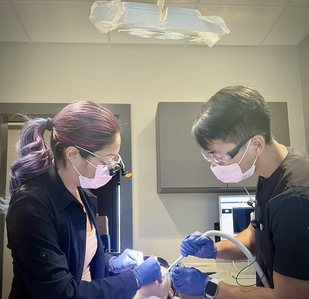 	
Two dental professionals wearing masks and gloves perform a Restorative Dentistry procedure on a patient in a modern clinic setting.